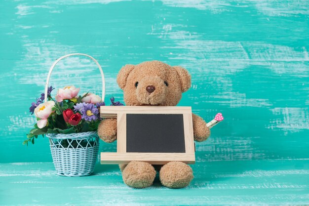 bear toy holding blackboard with flower