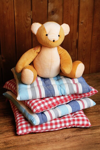 Bear toy on pillows on wooden table