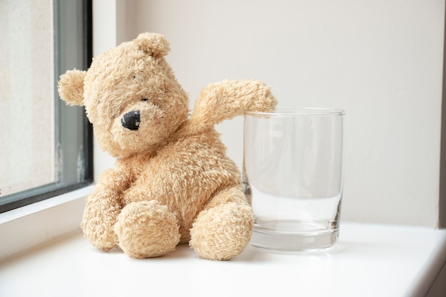 Bear with empty glass of water .