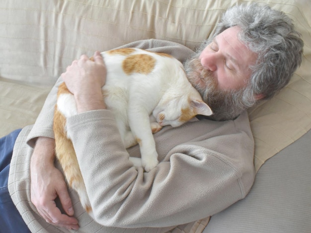 Beard man holding and cuddling his cat on the sofa at home