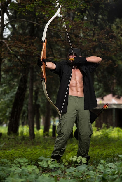 Photo beard man with a bow and arrows in the woods