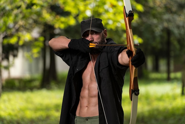 Photo beard man with a bow and arrows in the woods