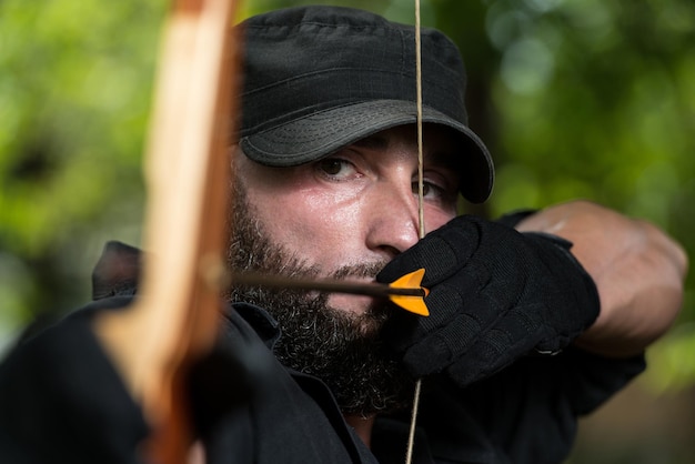 Photo beard man with a bow and arrows in the woods