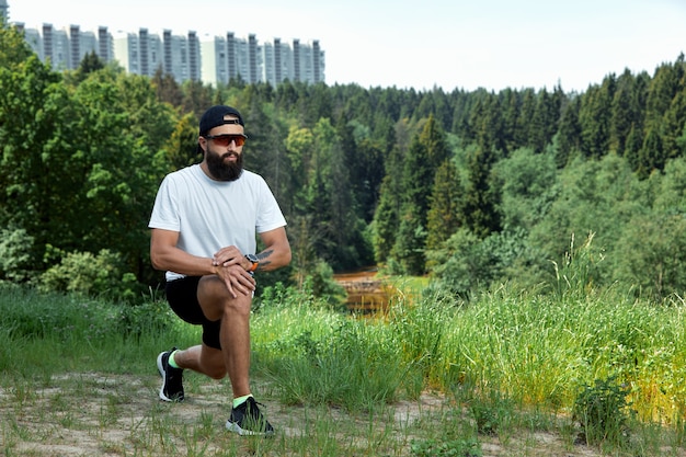 Bearded athletic man doing workout exercise in the outdoor gym in sunset