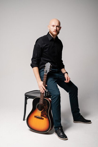 Bearded bald man with a guitar musician with acoustic\
guitar