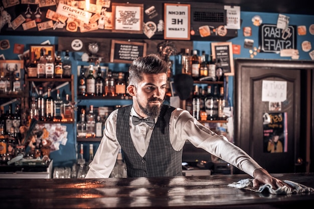 Foto il barman barbuto formula un cocktail nel pub