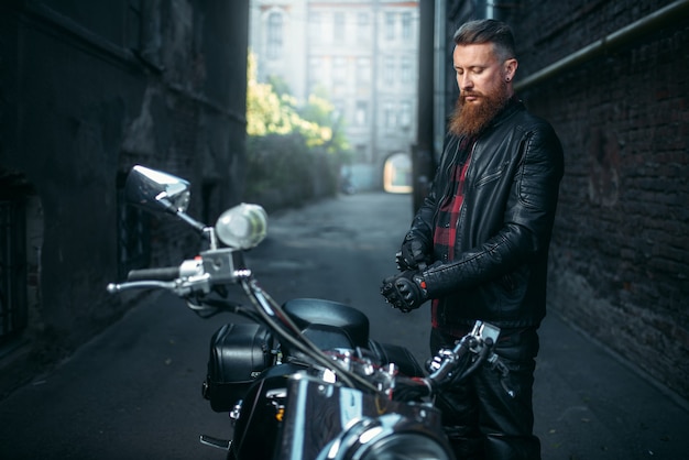 Bearded biker in leather clothes against chopper