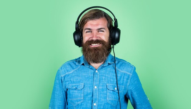 Bearded brutal man with moustache wear headphones listen music technology