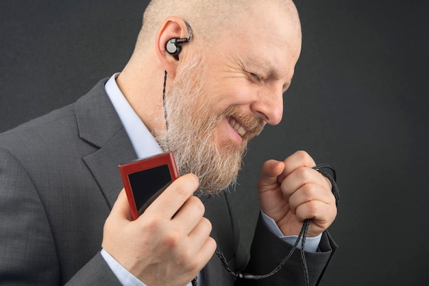 Bearded business man likes to listen to his favorite music at home with an audio player in small headphones. audiophile and music lover. music and hi-fi sound.