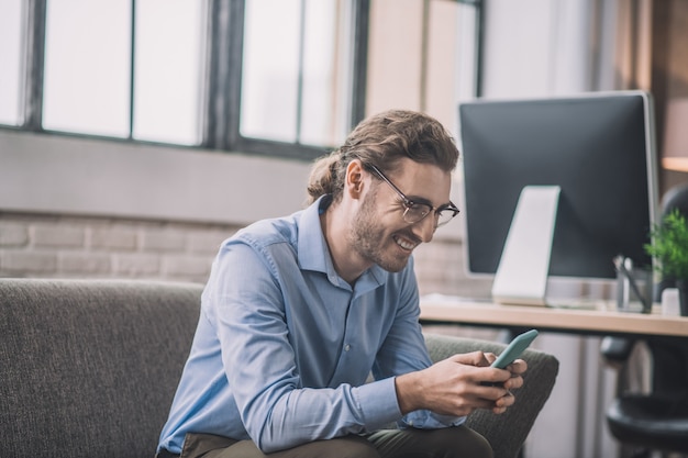 Bearded businessman in blue shirt looking on the phone