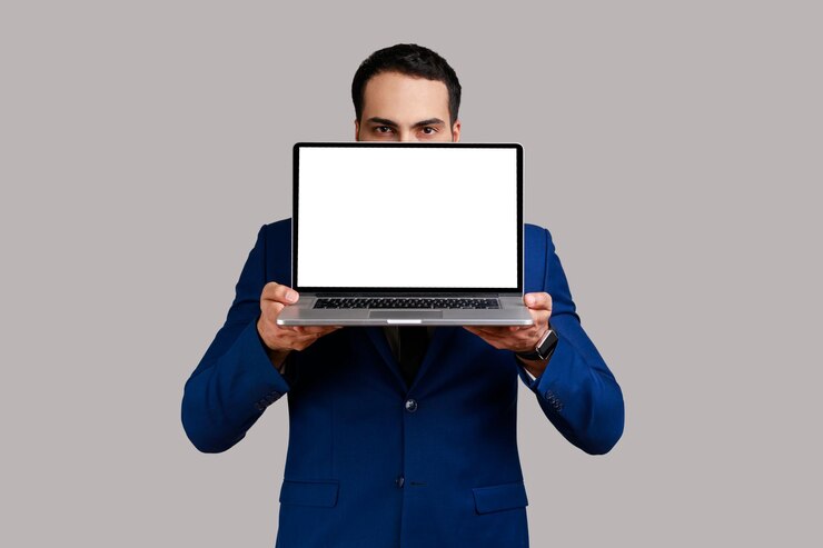 Photo bearded businessman covering half of face with laptop with empty display for advertisement or promotional text wearing official style suit indoor studio shot isolated on gray background