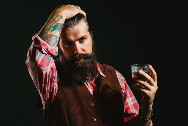 Бородатый бизнесмен в элегантном костюме со стаканом виски, потягивая виски, бородатый красавец холди