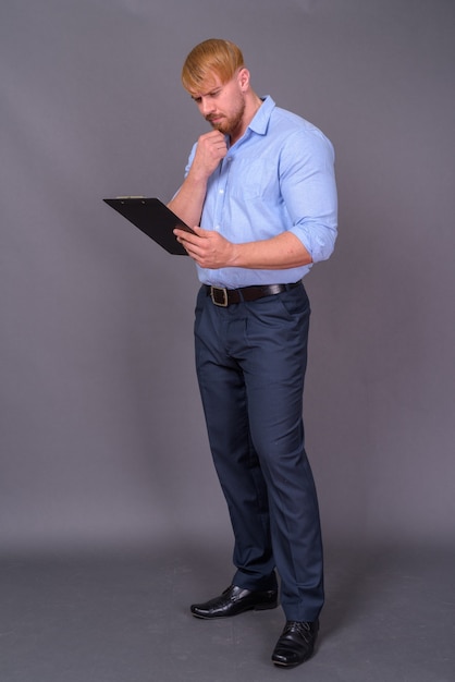 Bearded businessman with blond hair on gray