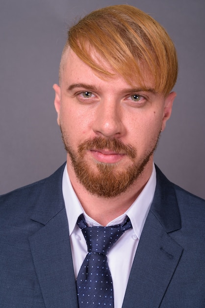 Bearded businessman with blond hair on gray