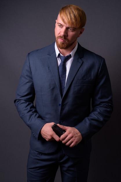 Bearded businessman with handgun on gray