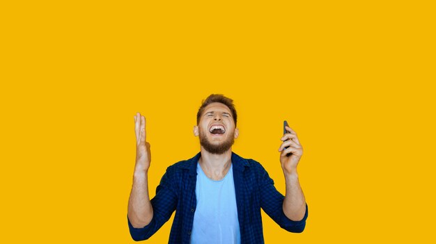 Bearded caucasian man using a phone is gesturing up after winning something