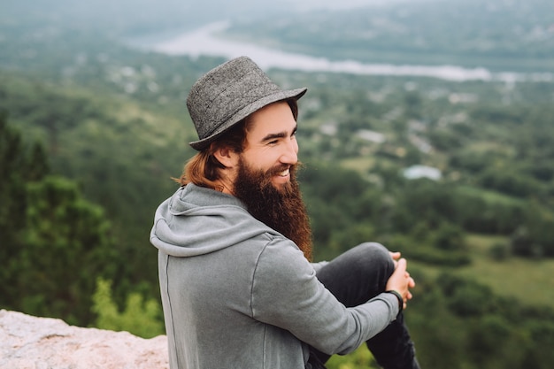 Bearded, cheerful tourist looks at summer beautiful landscape.