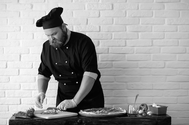 Bearded chef chef prepares meals at the table in the kitchen