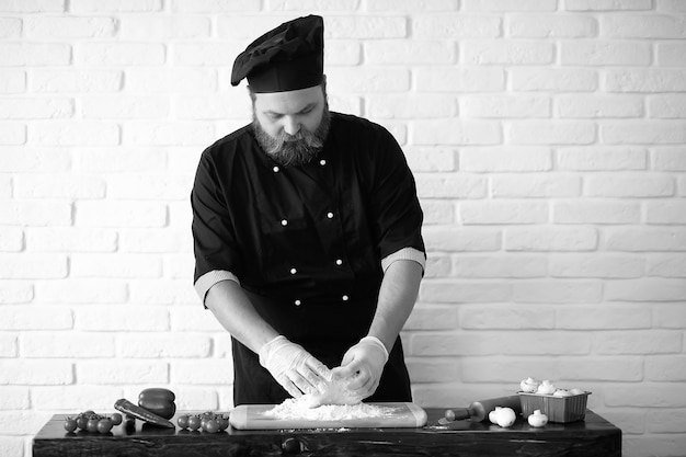 Lo chef chef barbuto prepara i pasti al tavolo in cucina