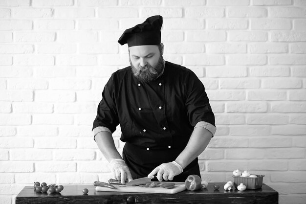 Lo chef barbuto prepara i pasti al tavolo in cucina