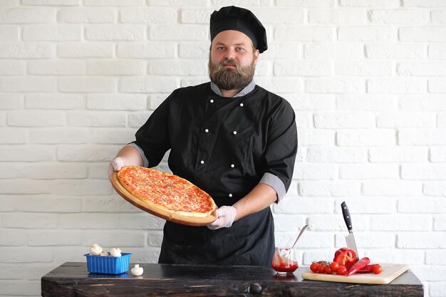 Bearded chef chef prepares meals at the table in the kitchen