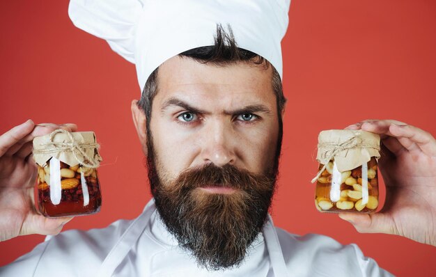 Бородатый шеф-повар держит банку с медовыми орехами, здоровой пищей и сладкими блюдами, концепция питания шеф-повара с