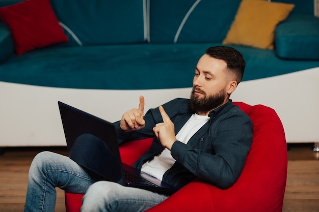 Bearded confident businessman in casual wear is using a laptop for video conference.