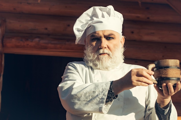 Bearded cook with wooden cup