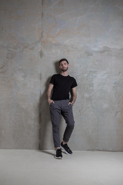 Bearded cute man leaning on the gray concrete wall