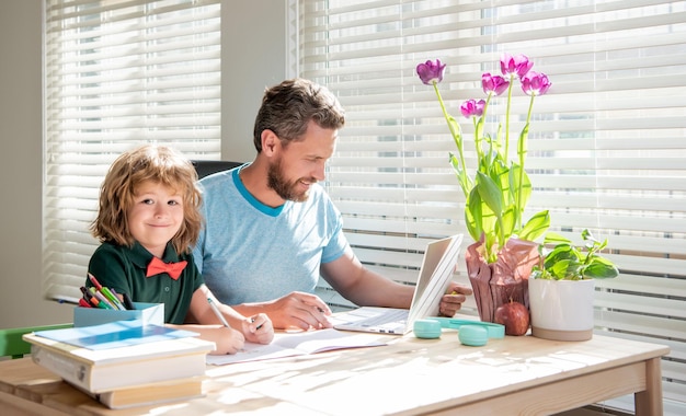 Bearded dad writing school homework with his child son in classroom childhood