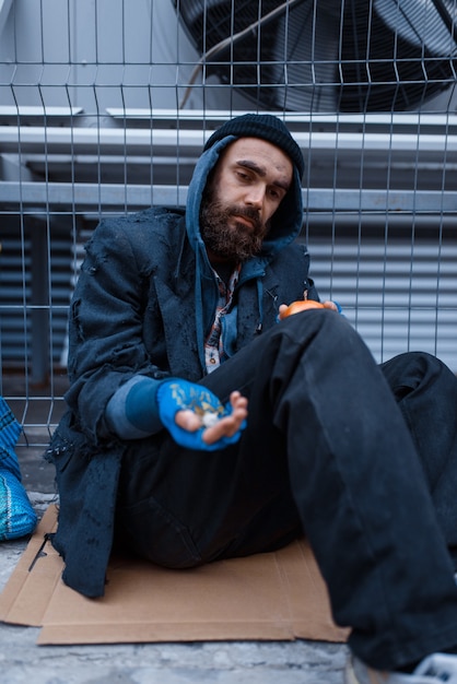 Bearded dirty poor begging on city street.