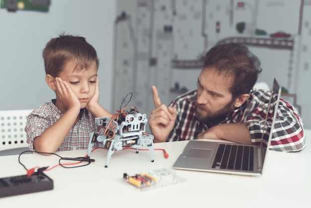 Bearded Father Help Upset Son with Robot at Home.