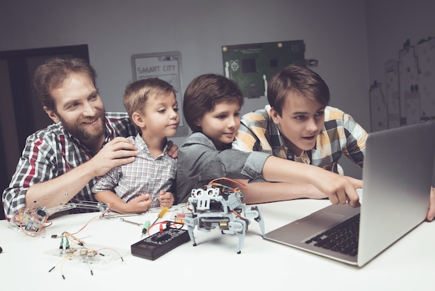 Photo bearded father and sons constructing robot at home