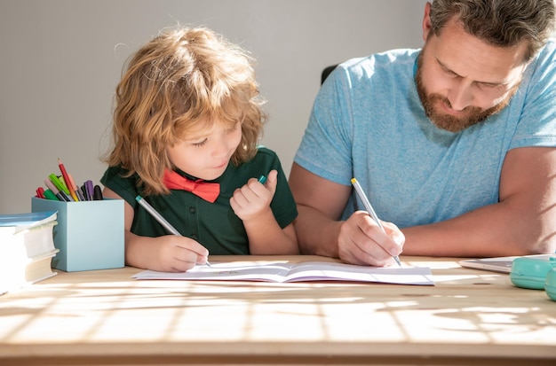 Bearded father writing school homework with his child son in classroom back to school