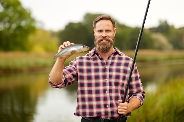 ひげのある漁師が釣り竿と魚を捕まえた