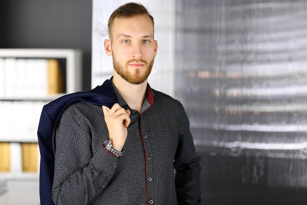 Bearded friendly adult businessman looking at camera. Business headshot or portrait in office.