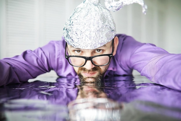 Bearded funny man in a cap of aluminum foil. concept art
phobias.conspiracy theory. conspiracy. insanity.