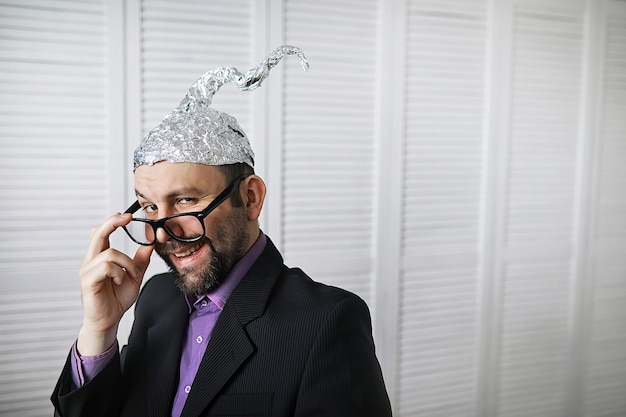 Bearded funny man in a cap of aluminum foil. Concept art phobias.Conspiracy theory. Conspiracy. Insanity.