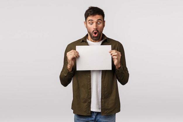 Bearded guy in brown coat holding blank paper