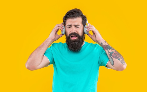 Bearded guy enjoying music in headphones isolated on yellow\
background guy listen music