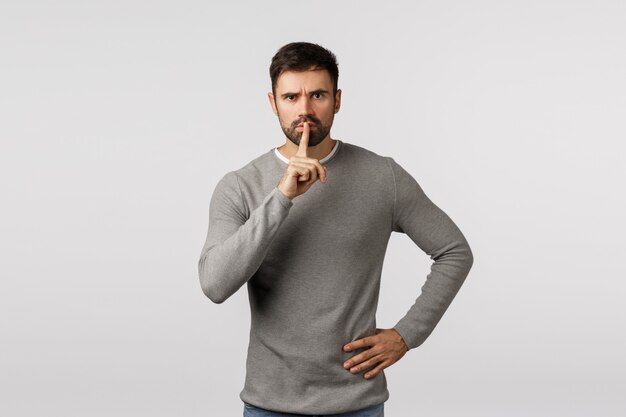 Bearded guy in grey sweater asking for silence