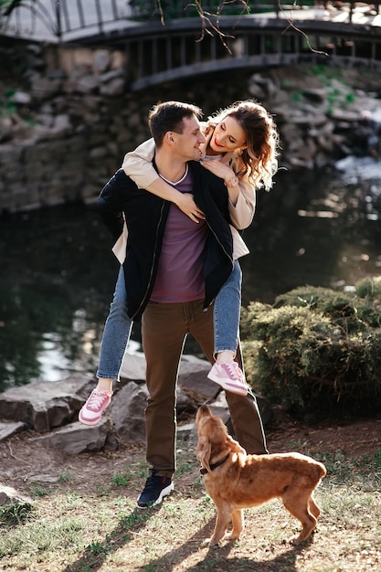 Foto il ragazzo barbuto in pantaloncini color cachi tiene per mano la ragazza bionda e corre