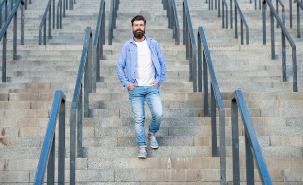 Bearded guy walk downstairs full length of guy with beard hipster guy outdoor at stairs