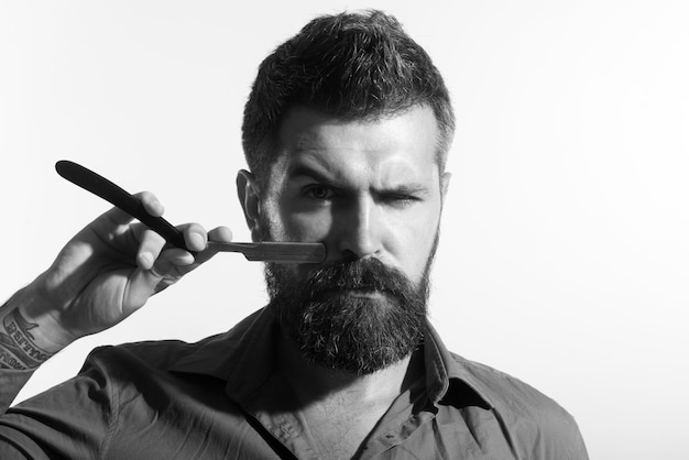 Bearded guy with barber equipment hairstylist with vintage straight razor hairdresser shaving with