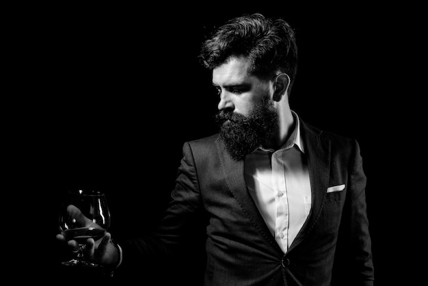 Bearded handsome man holding glass of cognac Tasting and degustation concept Barman or Bartender serves cognac