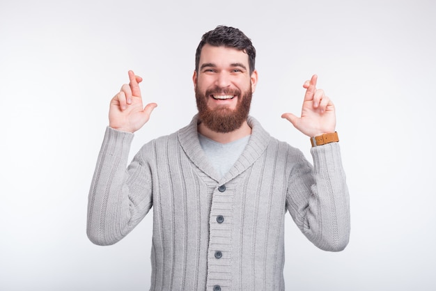 Bearded hipster is crossing fingers hoping for something.