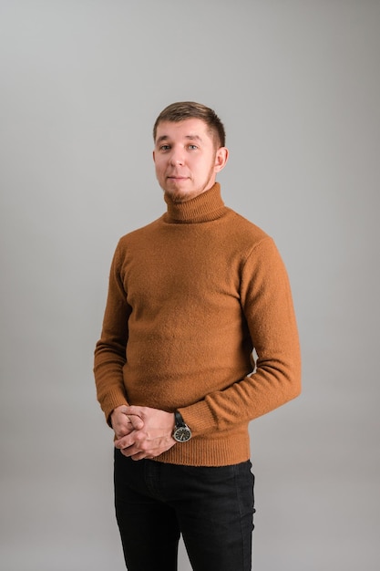 Bearded hipster in a red sweater on a gray background