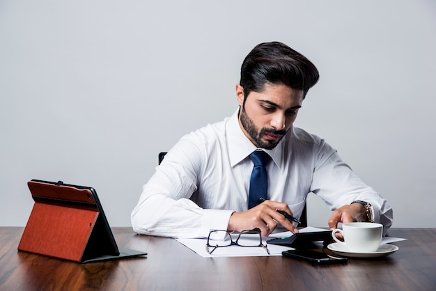 Bearded Indian Businessman accounting while sitting at desk table in office