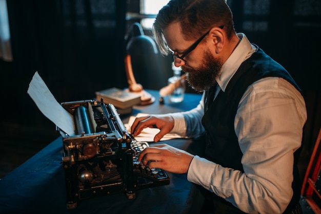 Bearded journalist in glasses typing on typewriter