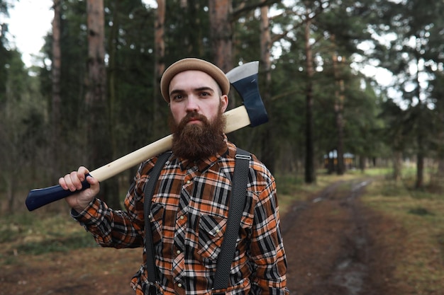 A bearded lumberjack with a large ax examines the tree before felling